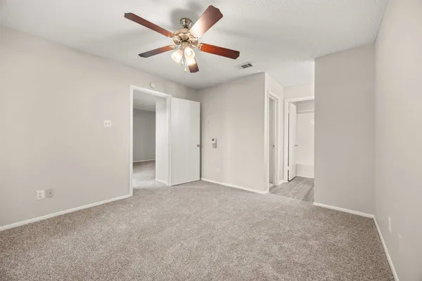 an empty room with chandelier fan and windows
