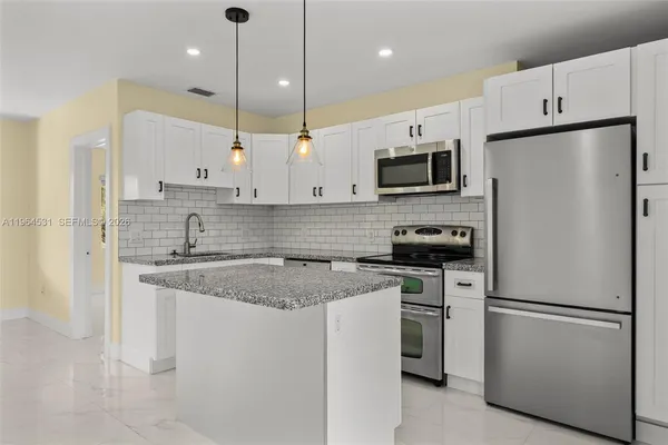 a kitchen with stainless steel appliances granite countertop a refrigerator a stove a sink and a microwave