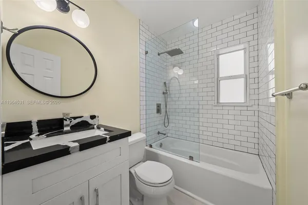 a bathroom with a granite countertop bathtub shower sink vanity and toilet