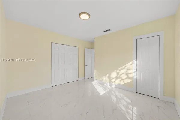 a view of a hallway with a door and a bathroom