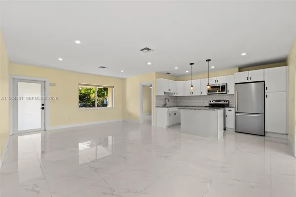 a kitchen with stainless steel appliances kitchen island sink refrigerator and cabinets