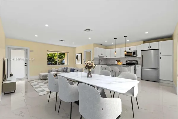 a kitchen with stainless steel appliances a dining table chairs and refrigerator
