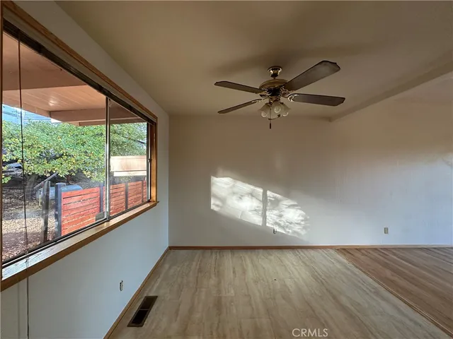 en view of empty room with wooden floor and fan