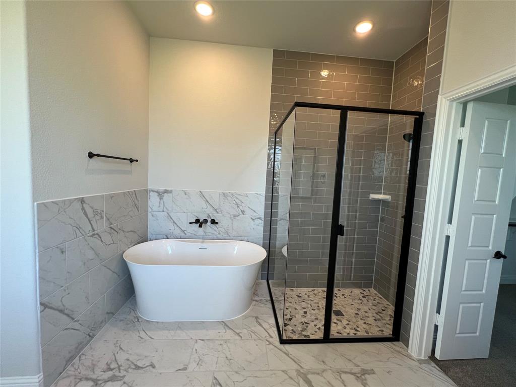 2108 Charters Circle Nevada, TX 75173 - Photo 20 of 37 Full bathroom featuring tile walls, a stall shower, a freestanding tub, recessed lighting, and a wainscoted wall