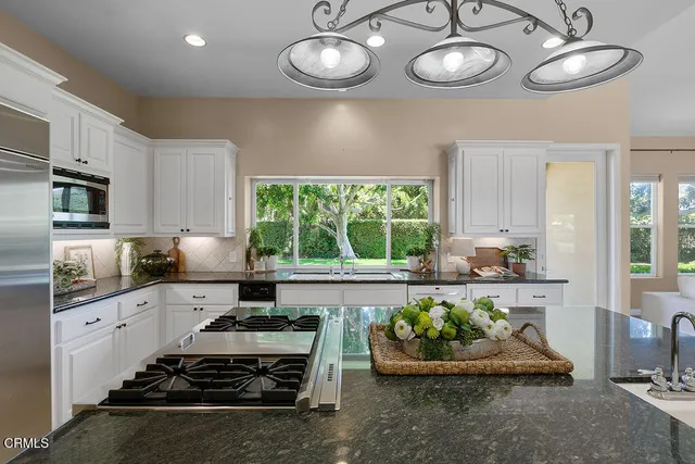 a large white kitchen with a large window and stainless steel appliances