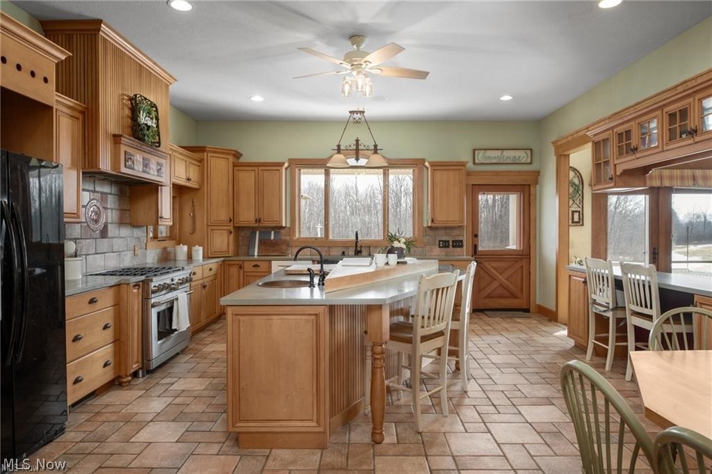 9419 Robinson Road Chardon, OH 44024 - Photo 16 of 49 Spacious kitchen featuring extensive wood cabinetry, a central island with integrated seating, and large windows