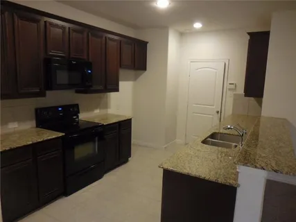 a kitchen with granite countertop a sink and a stove top oven