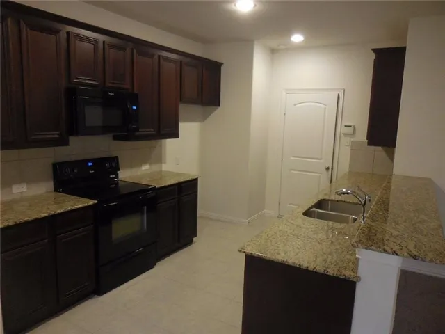 a kitchen with granite countertop a sink and a stove top oven