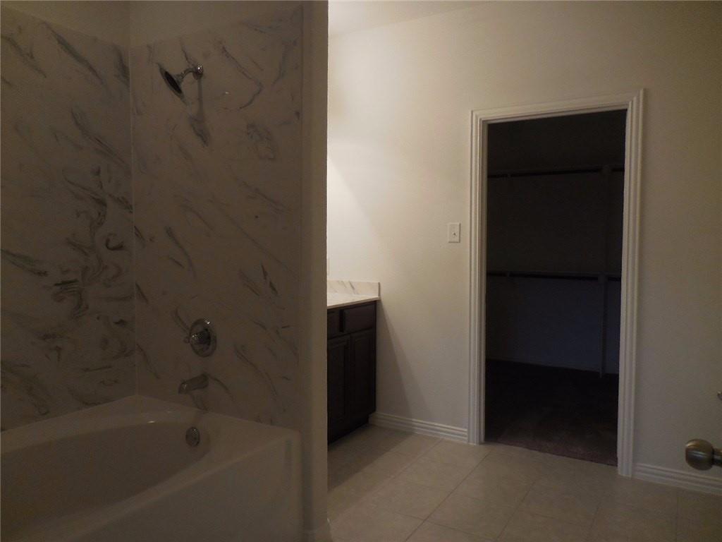 2224 Abbey Lane Mesquite, TX 75181 - Photo 5 of 9 Primary bathroom with vanity, a bath, a spacious closet, and light tile patterned floors