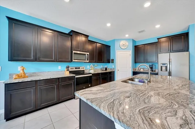 a kitchen with stainless steel appliances kitchen island granite countertop a sink refrigerator and cabinets