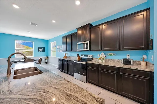 a kitchen with granite countertop a sink stainless steel appliances and cabinets