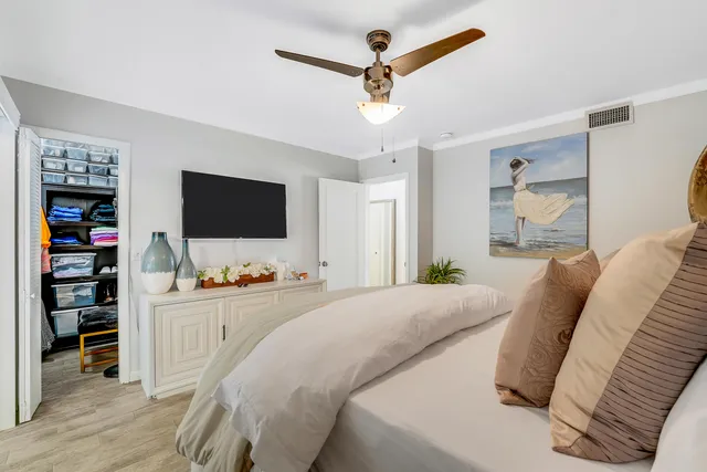 a bedroom with a bed a flat screen tv and a ceiling fan