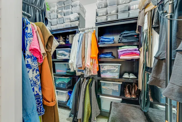 a view of walk in closet with clothes and shoes