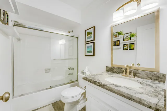 a bathroom with a granite countertop sink toilet and shower
