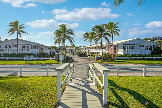 a view of an swimming pool with a lawn chairs under palm trees