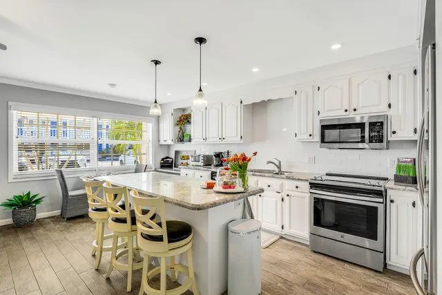 a kitchen with stainless steel appliances a stove a sink and white cabinets