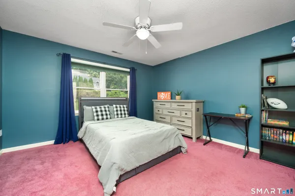 a bedroom with a bed a chandelier and a dresser