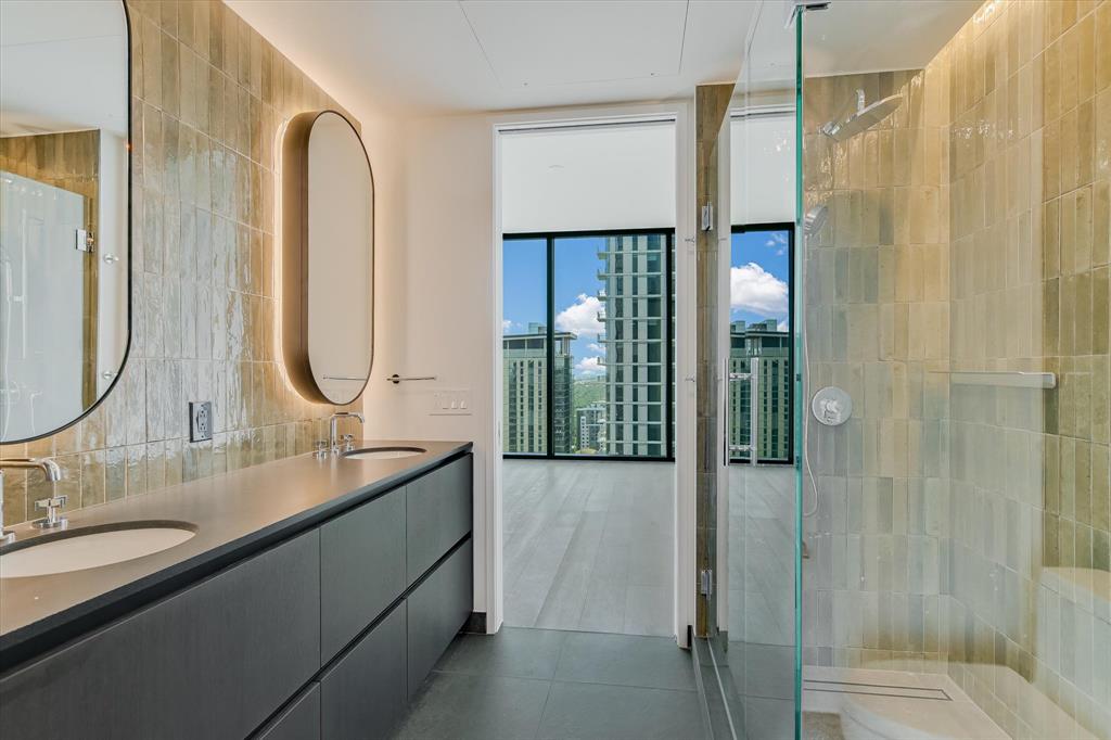610 Davis Street, Unit 4201 Austin, TX 78701 - Photo 10 of 40 Full bathroom featuring double vanity, a tile shower, tile walls, dark tile patterned flooring, and floor to ceiling windows