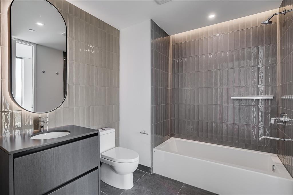 610 Davis Street, Unit 4201 Austin, TX 78701 - Photo 12 of 40 Full bath with tile walls, tub / shower combination, vanity, dark tile patterned floors, and recessed lighting