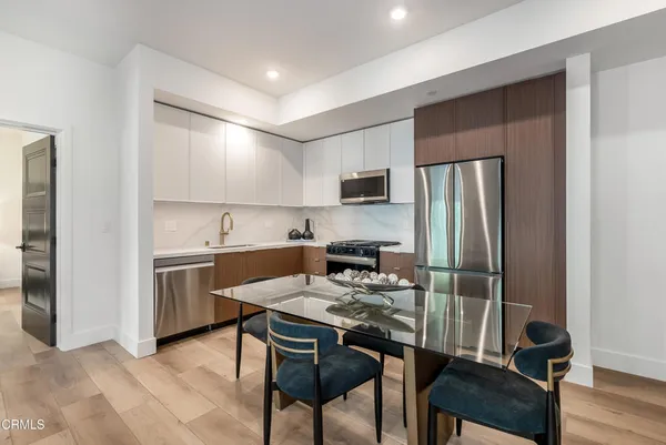 a kitchen with a refrigerator a stove top oven a sink dishwasher and chairs with wooden floor