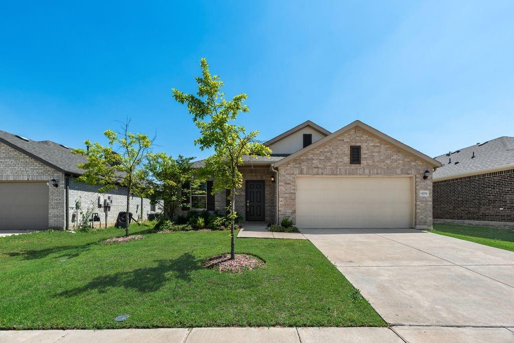 14216 Aberavon Drive Pilot Point, TX 76258 - Photo 1 of 19 Brick exterior with a stone accent facade, featuring a two-car garage, mature landscaping, and a concrete driveway