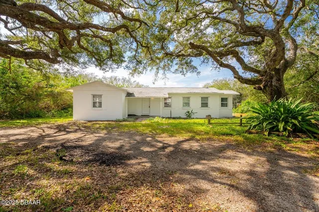 a view of a house with a yard and large tree