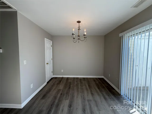 a view of a hallway with wooden floor and a chandelier