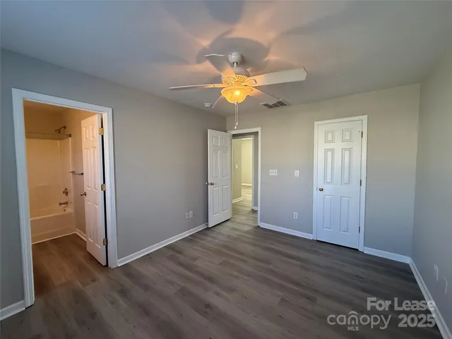 an empty room with wooden floor and a ceiling fan