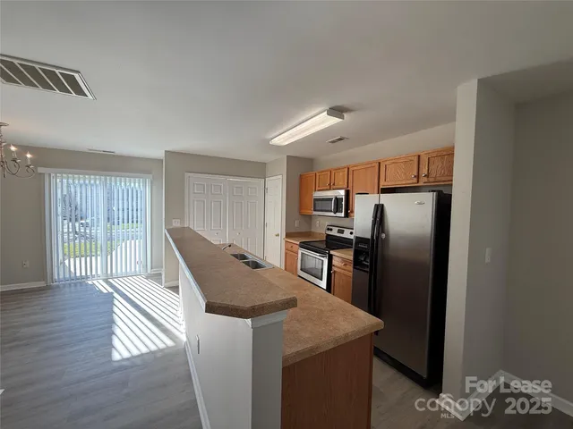 a kitchen with stainless steel appliances granite countertop a refrigerator a sink a stove and island