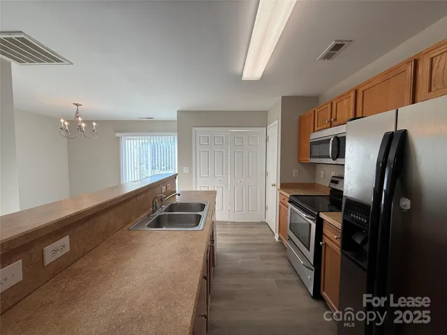 a kitchen with granite countertop stainless steel appliances a sink stove and refrigerator