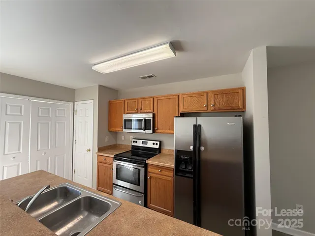 a kitchen with stainless steel appliances granite countertop a refrigerator and a stove top oven