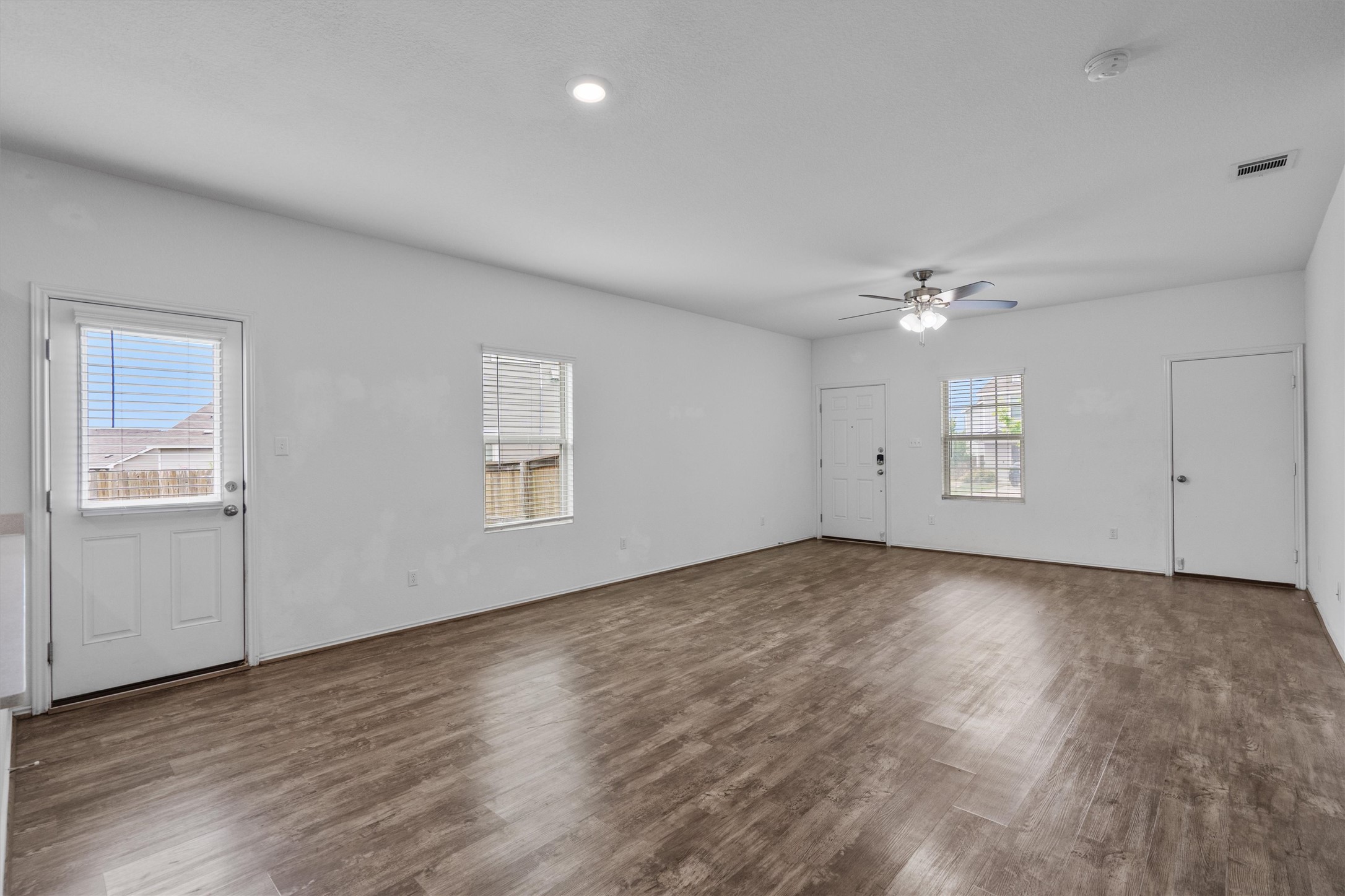 791 Circle Way Jarrell, TX 76537 - Photo 5 of 36 Spacious room featuring wood-finish flooring, white walls, and multiple windows with blinds