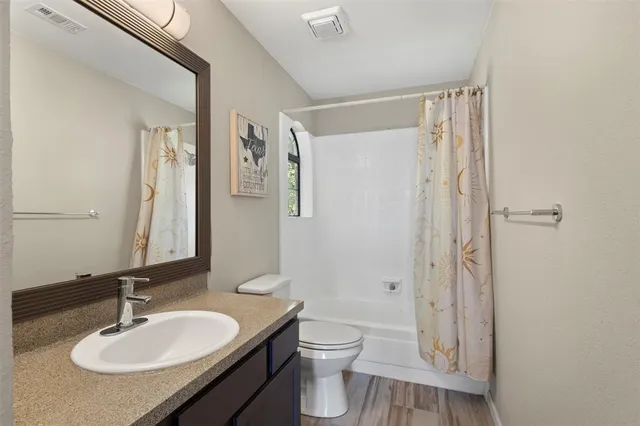 a bathroom with a granite countertop sink toilet a mirror a vanity and shower