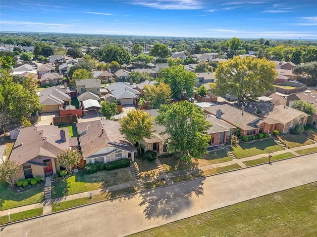 an aerial view of residential houses with outdoor space and trees