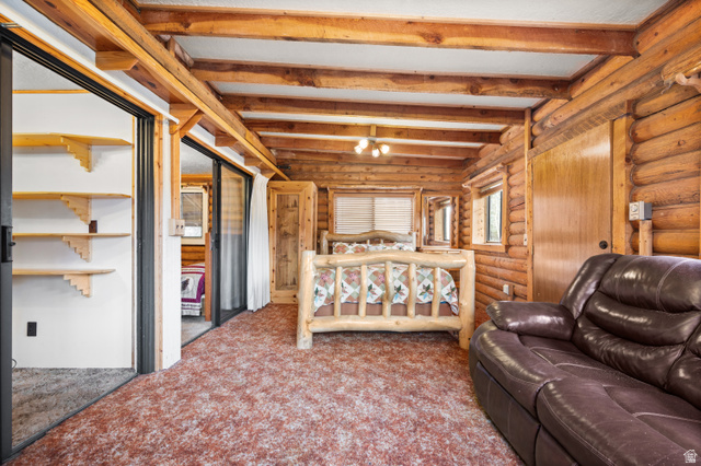 4725 Pine Ridge Road Evanston, UT 82930 - Photo 31 of 82 Interior space featuring log walls, exposed wood beams, and a ceiling fan with integrated lighting