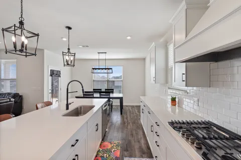 a kitchen with stainless steel appliances kitchen island granite countertop a table chairs sink and cabinets