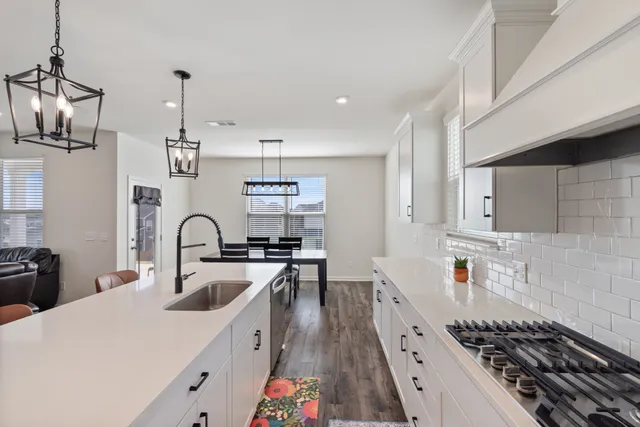 a kitchen with stainless steel appliances kitchen island granite countertop a table chairs sink and cabinets