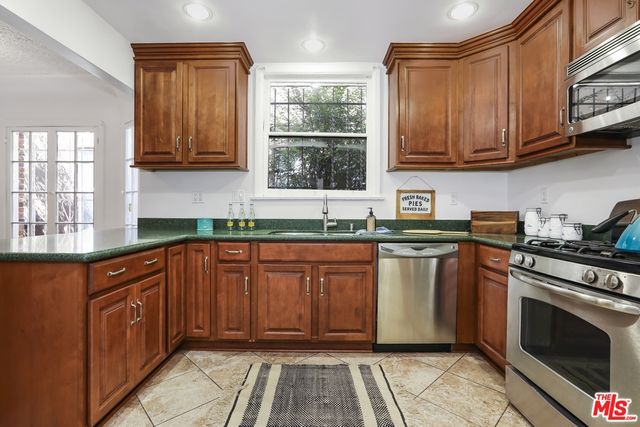 a kitchen with stainless steel appliances granite countertop wooden cabinets a stove top oven a sink and dishwasher with wooden floor