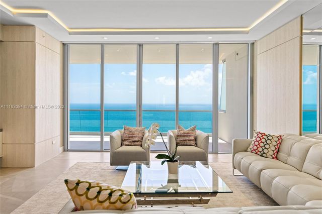 a living room with furniture large windows and a table