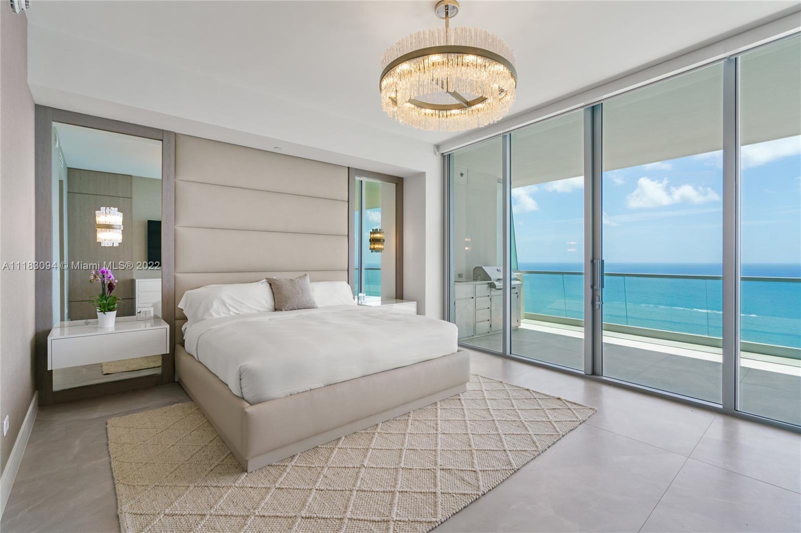 18501 Collins Avenue, Unit 3302 Sunny Isles Beach, FL 33160 - Photo 20 of 48 a spacious bedroom with a large bed and a chandelier