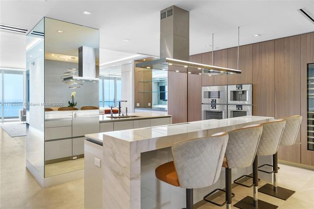 a large kitchen with kitchen island a large counter top space and stainless steel appliances
