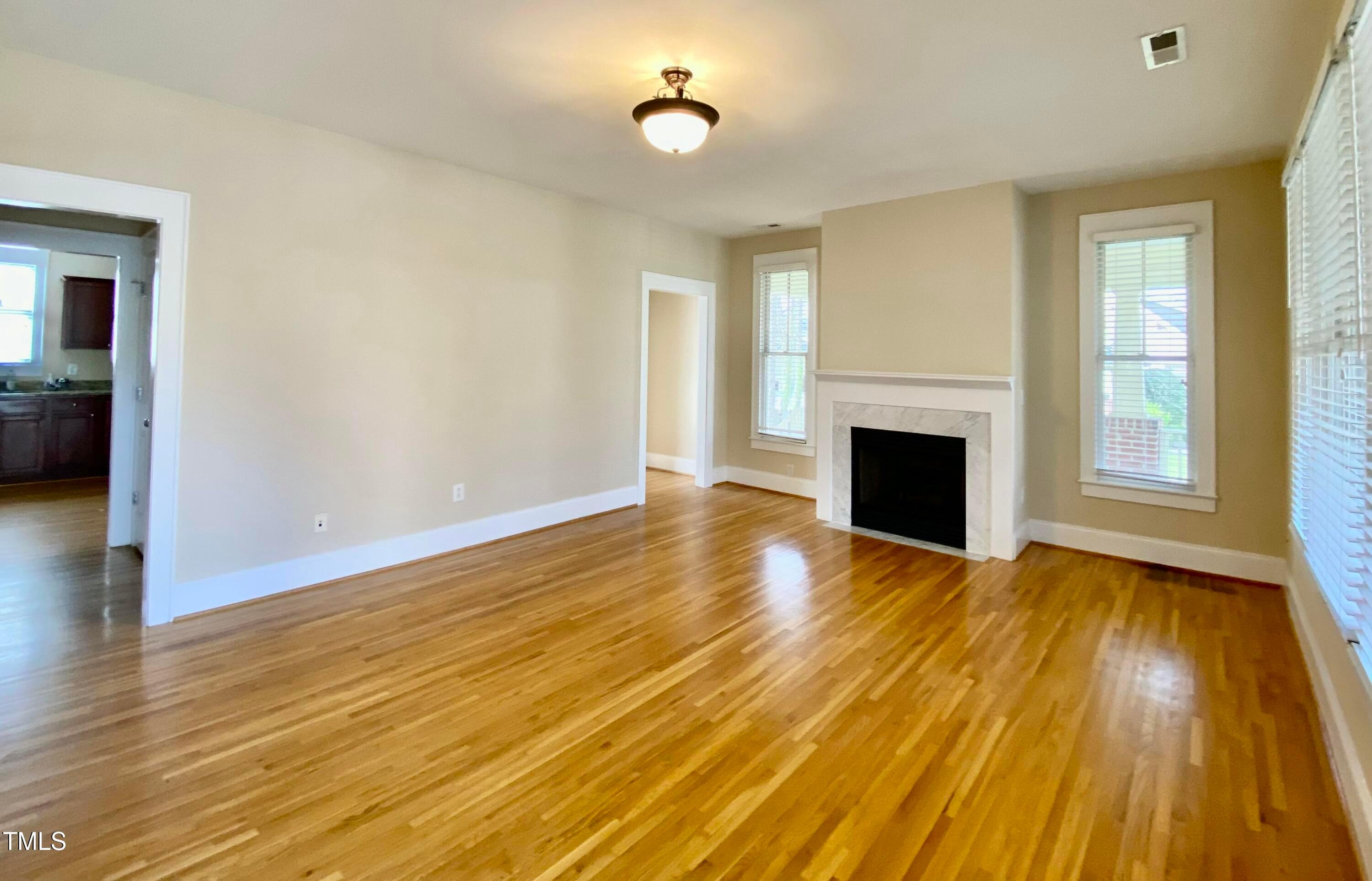 813 Clarendon Street Durham, NC 27705 - Photo 5 of 36 a view of empty room with wooden floor and fireplace