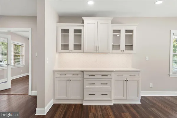 an empty room with wooden floor ceiling fan and windows