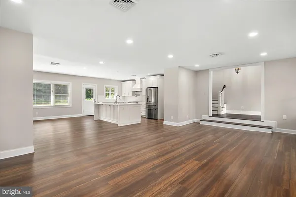 a view of an empty room with wooden floor fireplace and a window