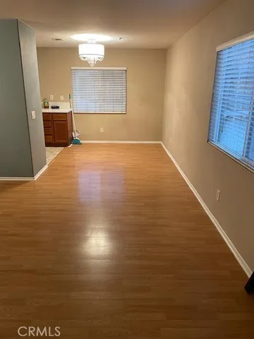 a view of kitchen and empty room with wooden floor