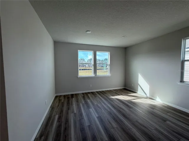 an empty room with wooden floor cabinet and windows