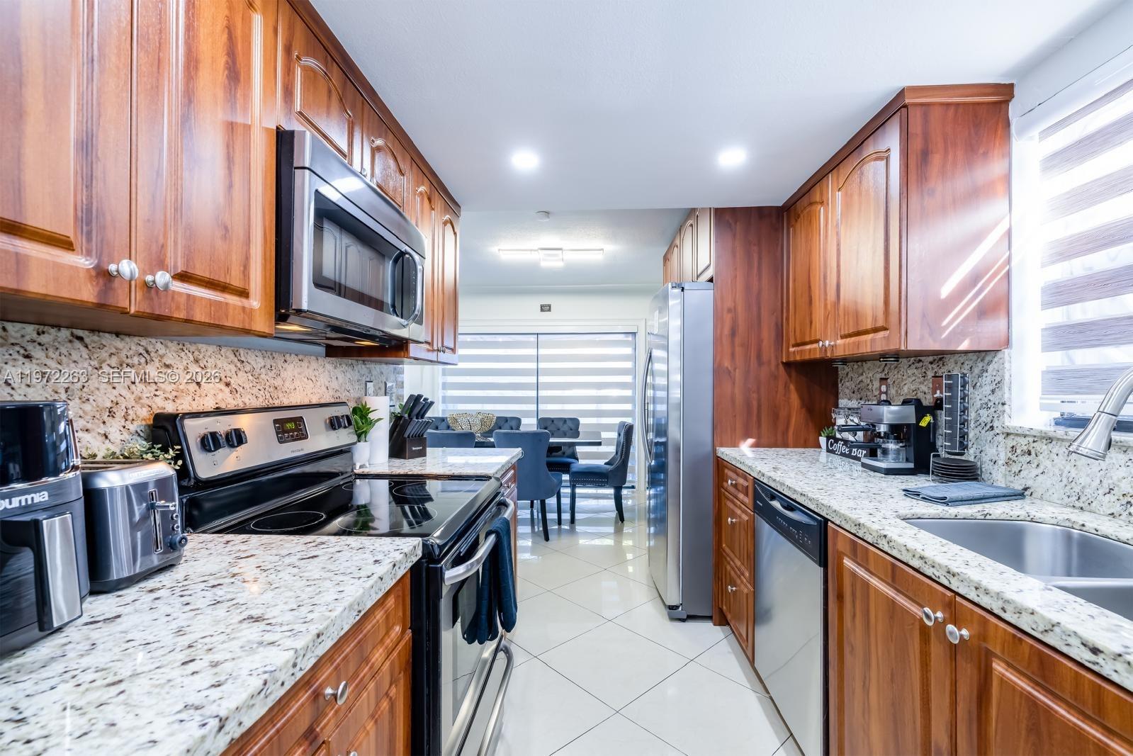 15445 Southwest 57th Street Miami, FL 33193 - Photo 20 of 78 a kitchen with kitchen island granite countertop a stove top oven a sink a counter top space and cabinets