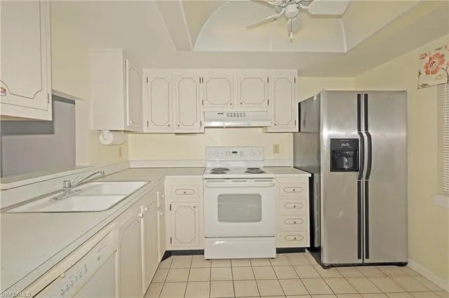 a kitchen with granite countertop white cabinets and white appliances