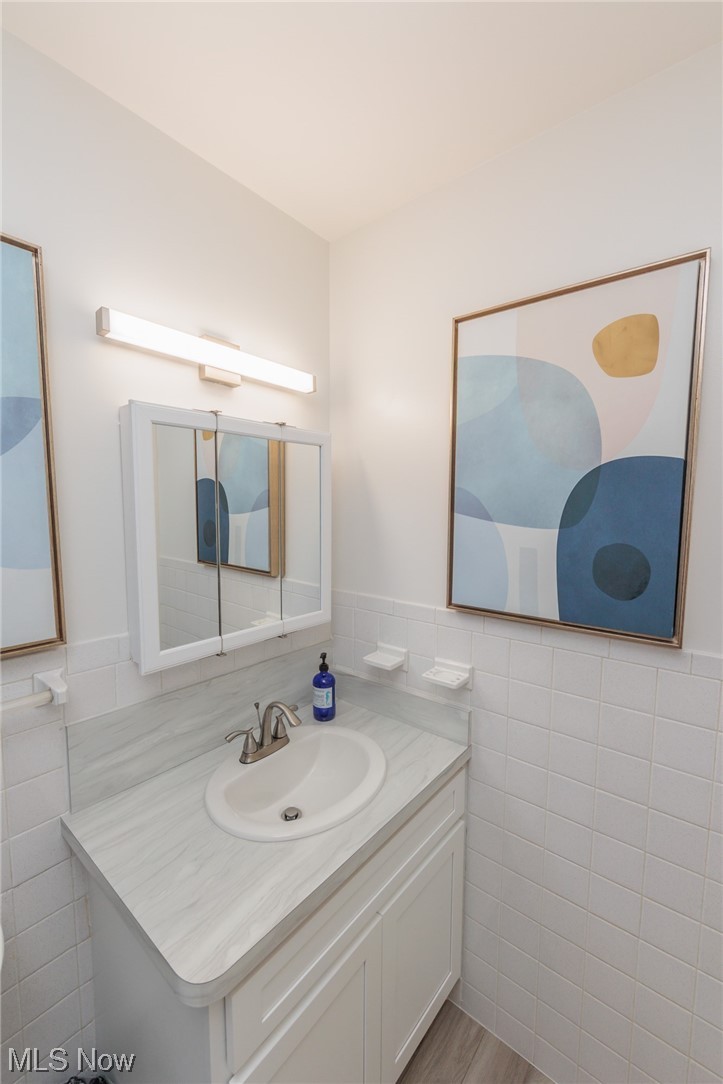 1750 Wagar Road, Unit 206 Rocky River, OH 44116 - Photo 24 of 33 Bathroom featuring Tub, large vanity, mirror, tile walls, backsplash, and light LVP floors