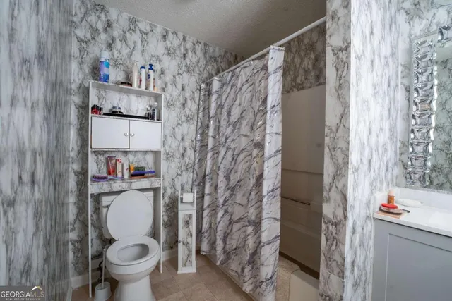 a bathroom with a toilet and a shower curtain